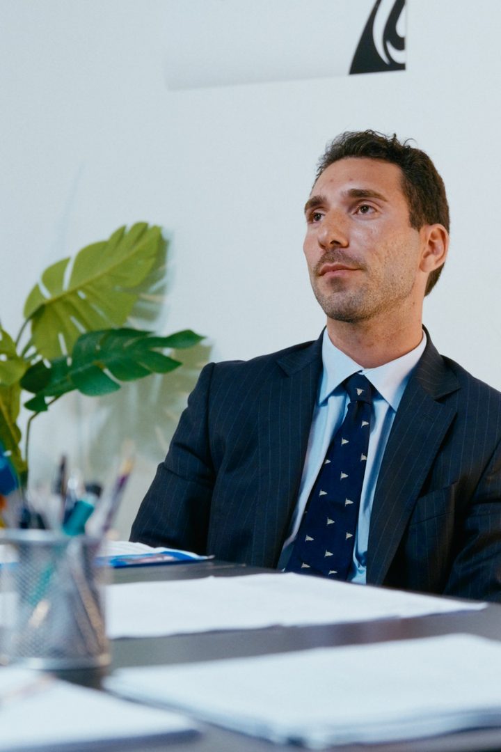 Un uomo in giacca blu seduto alla scrivania