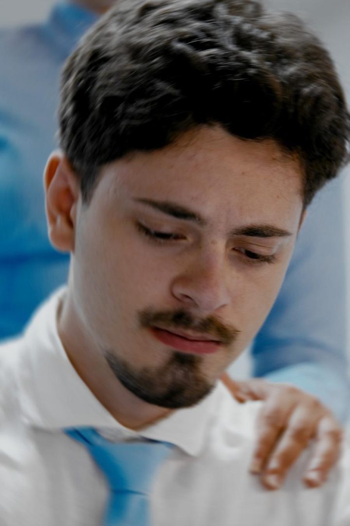 Un ragazzo a testa bassa, una mano sulla spalla